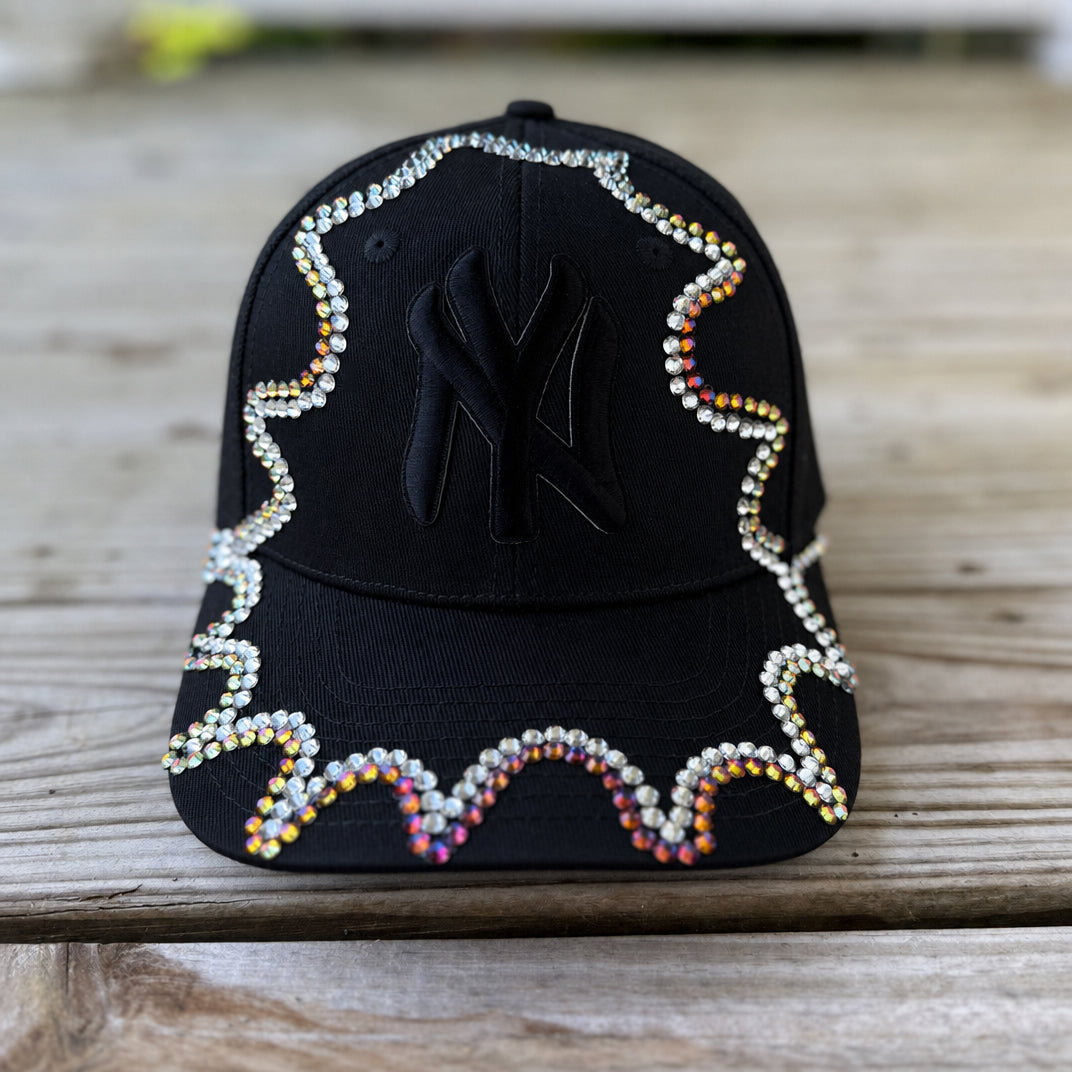 Close-up of iridescent chameleon crystal appliqué on black New York hat