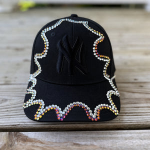 Close-up of iridescent chameleon crystal appliqué on black New York hat