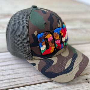 Left side view of camouflage trucker hat with colorful chenille DOPE patch and mesh back - Rebel P Customs