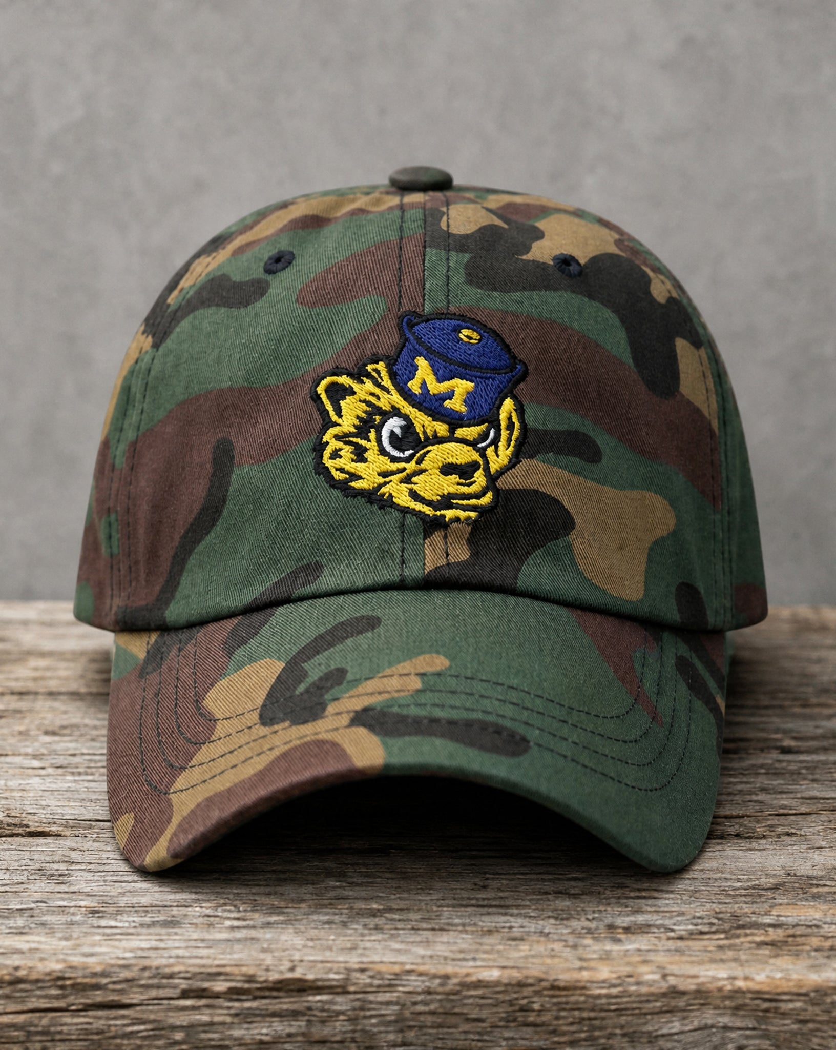 Hand-drawn Michigan wolverine mascot patch on a woodland camo hat, handcrafted City Collection by Believe In New York